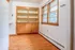 Charming corner with wooden shelving, large windows, and elegant hardwood flooring, perfect for a cozy reading nook or dining space.
