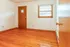 Inviting room with rich hardwood floors, a wooden door, and sunlit window, perfect for customization.