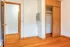 Bright apartment room with warm hardwood floors, open closet space, and sleek wooden door.