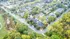 Captivating aerial view of a lush, tree-lined neighborhood showcasing cozy residential homes and vibrant green spaces.