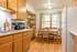 Inviting kitchen with warm wooden cabinets, a sunlit dining nook, and modern appliances, perfect for cozy meals.