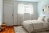Bright and airy bedroom with soft natural light, featuring modern white decor and elegant hardwood flooring.