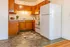 Charming kitchen with warm wooden cabinetry, sleek countertops, and a large white refrigerator, creating a cozy and inviting atmosphere.