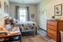 Modern bedroom with a stylish desk, cozy bed, and natural light from a large window; perfect for productivity and relaxation.