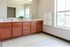 Bright and inviting bathroom with dual sinks, elegant wooden cabinetry, and a large mirror perfect for morning routines.