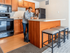 Modern kitchen space featuring sleek wooden cabinetry, a spacious countertop with bar stools, and state-of-the-art appliances, ideal for social gatherings.