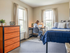 Bright and cozy bedroom with a desk area, modern furniture, and large windows for abundant natural light.