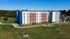 Modern apartment building with a stylish facade, surrounded by lush green lawns and vibrant outdoor spaces.
