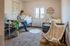 Cozy bedroom with modern decor, featuring a stylish faux fur chair, lush plant accents, and ample natural light from large window.