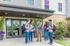 Dynamic student community outside modern building entrance, surrounded by lush greenery.