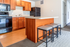 Modern kitchen with wooden cabinets, black appliances, and a cozy island with seating. Bright and inviting space ideal for cooking and dining.