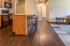 Modern apartment kitchen with sleek wooden flooring, cozy seating area, and elegant cabinetry.