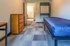 Modern apartment bedroom showcasing sleek flooring, cozy bed with blue cover, and tasteful wooden dresser.