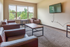 Inviting living space with large window views, featuring cozy modern seating and a mounted TV.