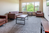 Bright and modern living room with stylish brown leather sofas, large window offering abundant natural light, and sleek minimalistic design.