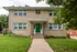 Charming two-story brick apartment building with green door and well-maintained lawn, ideal for a cozy living experience.