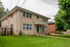 Charming two-story brick apartment building with lush green lawn and welcoming entrance in a serene residential area.