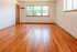 Bright and spacious room with polished hardwood floors and large windows allowing natural light.