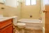 Inviting bathroom featuring a classic tiled bathtub, elegant wood vanity, and natural light from a frosted window.