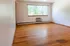 Inviting and spacious living room with polished hardwood floors, large window, and built-in air conditioning unit. Perfect for cozy relaxation and entertaining.