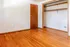 Bright empty room with polished hardwood floors and a spacious open closet.