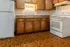 Cozy kitchen with warm wooden cabinets, tiled flooring, a classic white refrigerator, and an electric stove.