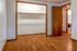Inviting bedroom with rich wood flooring, spacious closet, and an adjoining bathroom, perfect for comfortable living.