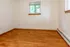 Cozy room with warm wood flooring, natural light from window, and soft white walls.