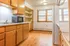 Bright kitchen with wooden cabinets and modern appliances, featuring large windows for natural light.