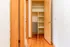 Inviting hallway with gleaming hardwood floors leading to a spacious closet with built-in shelving.