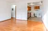 Bright open-plan living area with hardwood floors leading to a cozy kitchen featuring modern appliances and ample natural light.