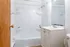 Bright, modern bathroom with pristine white tub, sleek vanity with mirror, and convenient shelving for toiletries.