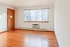 Bright and inviting living space with elegant hardwood floors, large window providing natural light, and cozy heater for comfort.