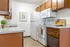 Charming kitchen with warm wooden cabinets, modern appliances, and a cozy countertop adorned with fresh fruit and a potted plant.