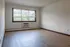 Bright and airy living room with large window, sleek wood flooring, and a built-in air conditioning unit.
