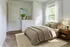 Bright and cozy bedroom with neutral tones, featuring a plush bed, stylish dresser, and large window with natural light.