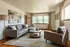 Bright and inviting living room with stylish gray sofa and armchair, modern art, and large windows letting in natural light.