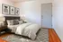 Cozy bedroom with a modern grey upholstered bed, stylish abstract wall art, and warm wooden flooring.