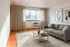 Bright living room with a modern gray sofa, minimalist coffee table, and large window offering natural light.