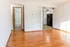 Bright apartment interior with sleek hardwood floors, open living area, and a cozy kitchen space.