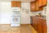 Charming kitchen with warm wooden cabinetry, modern appliances, and tasteful botanical wall art, perfect for culinary adventures.