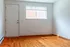 Bright empty room with polished hardwood floors, large window, and white walls, offering a clean slate for customization.