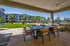 Inviting outdoor seating area with stylish dining set, modern grill, and lush green views framed by palm trees and contemporary apartment architecture.