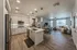 Modern open-plan kitchen and living area featuring elegant wood flooring, sleek cabinetry, and stylish lighting fixtures.