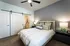 Elegant bedroom showcasing a cozy bed with plush pillows, modern ceiling fan, and stylish lighting, complemented by a sliding barn door leading to a sleek en-suite bathroom.