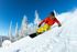 Exhilarating image of a snowboarder carving down a snowy slope with frosty trees and a vibrant blue sky, captured at Liv Sky Cottages.