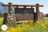 Charming stone and wood sign for Flagstaff, Arizona, surrounded by vibrant yellow wildflowers and set against a backdrop of scenic mountains.