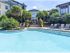A resort-style swimming pool area featuring a covered cabana patio with lounge seating next to the water.