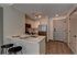 Breakfast bar in kitchen with white cabinetry, stainless steel appliances, and plank-style flooring at The Henry | Apartments in Tampa, FL.