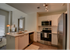 Kitchen with white-on-white cabinetry, stainless steel appliances, and wood-plank style flooring at The Henry | Apartments in Tampa, FL.